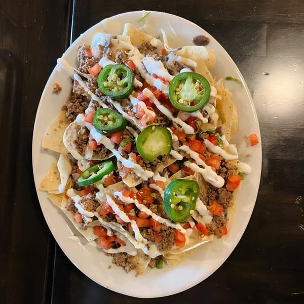 Hops N Guac nachos with ground beef, diced tomatoes, jalapeños, and a drizzle of sour cream.